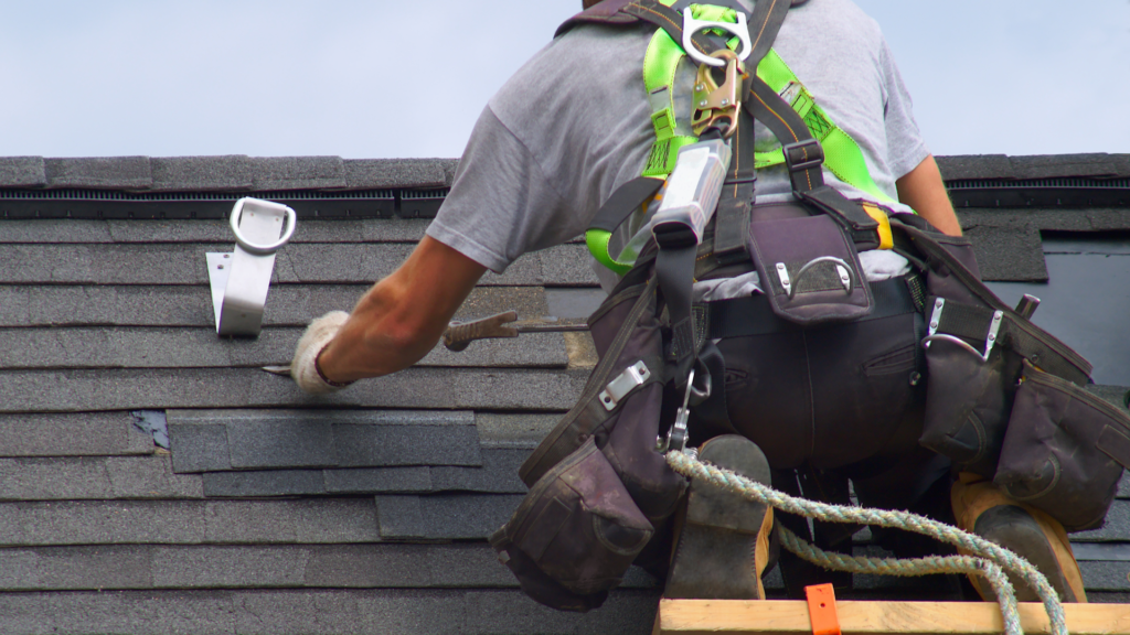professional inspecting roof and wearing security rope