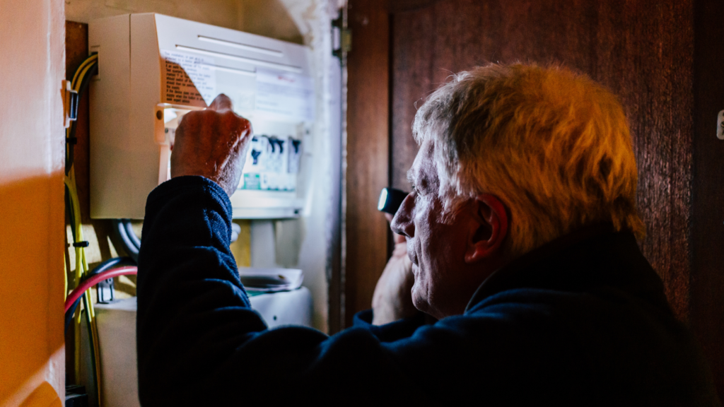 Senior man checking home fuse box during power outage